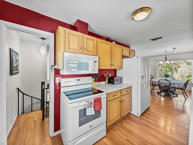 kitchen featuring hanging light fixtures, white appliances, light wood-type flooring, and light countertops