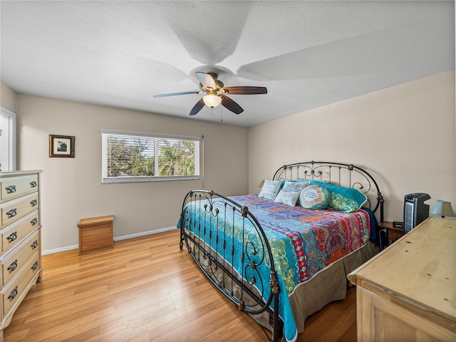 bedroom featuring a textured ceiling, wood finished floors, a ceiling fan, and baseboards