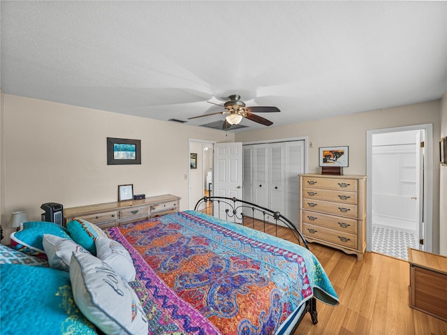 bedroom with ceiling fan, a textured ceiling, visible vents, a closet, and light wood finished floors