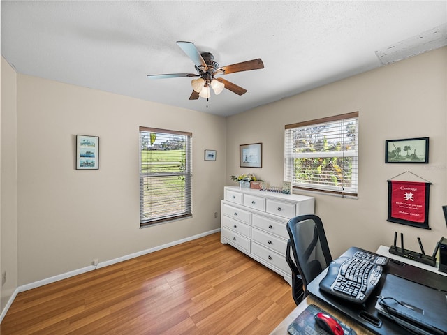 office area featuring light wood-style floors, a textured ceiling, baseboards, and a ceiling fan