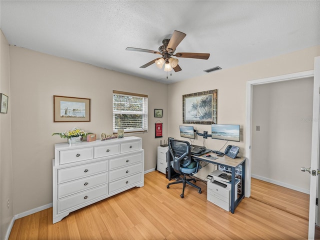 office with a ceiling fan, baseboards, visible vents, and light wood finished floors