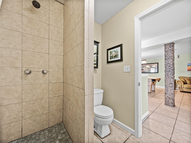 full bath featuring tile patterned flooring, baseboards, tiled shower, and toilet