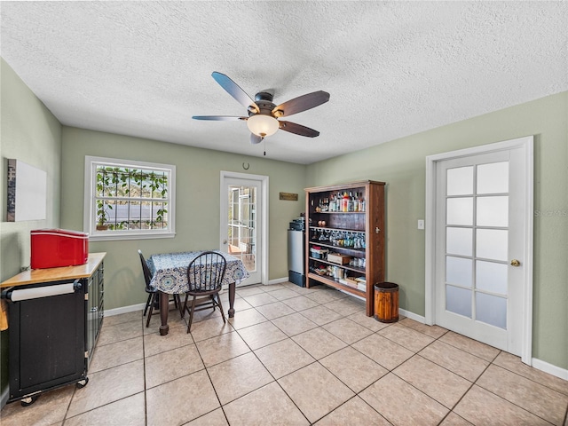 dining space with light tile patterned floors, a textured ceiling, a ceiling fan, and baseboards