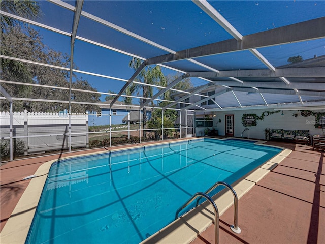 pool with glass enclosure, fence, and a patio