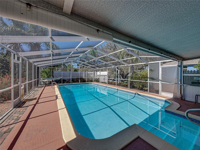 view of swimming pool featuring glass enclosure, a fenced backyard, and a fenced in pool