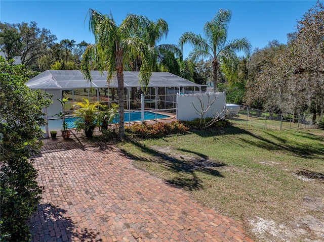 exterior space with a fenced in pool, glass enclosure, a lawn, and fence