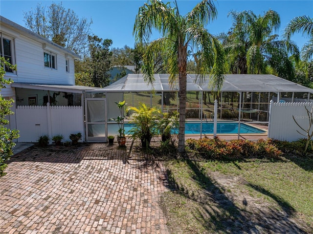 outdoor pool featuring glass enclosure, a patio area, and fence