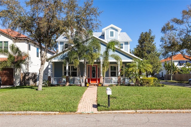 view of front facade featuring a porch, a front yard, metal roof, and fence