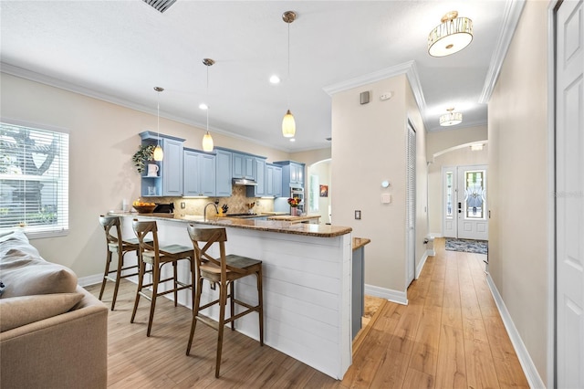 4301 W San Luis St, Tampa, FL 33629 - kitchen with arched walkways, a breakfast bar area, blue cabinets, a peninsula, and light wood-style floors