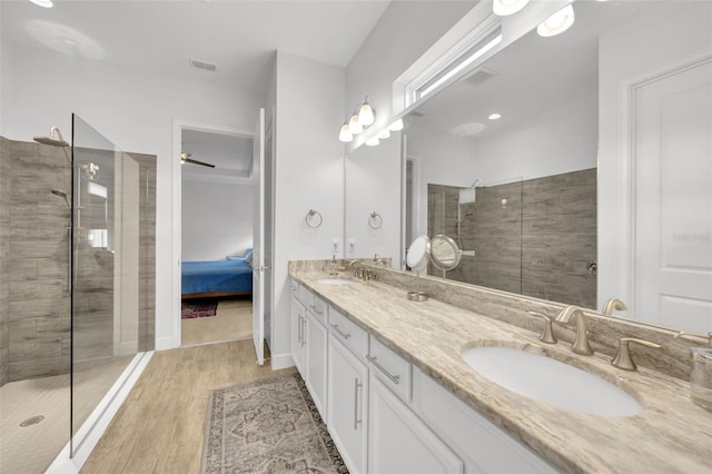 bathroom with a tile shower, vanity, and wood-type flooring