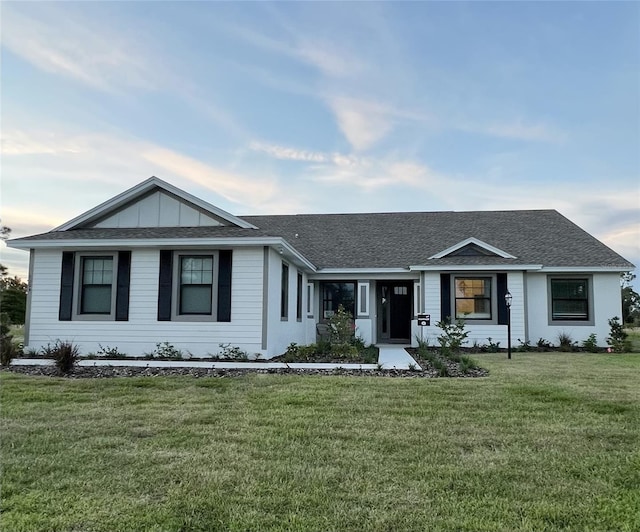 ranch-style house featuring a front lawn, board and batten siding, and roof with shingles