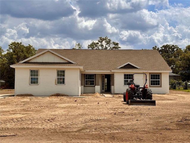 ranch-style house featuring a shingled roof and board and batten siding