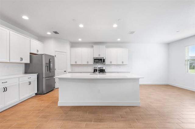 2569 Rogers Rd, Lakeland, FL 33812 - kitchen with stainless steel appliances, light countertops, white cabinets, a center island with sink, and recessed lighting