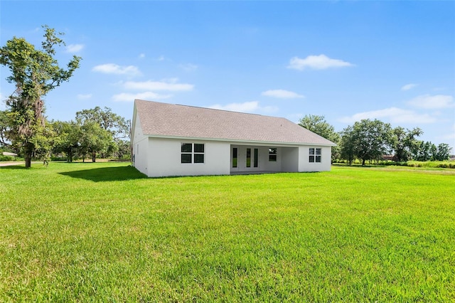 2569 Rogers Rd, Lakeland, FL 33812 - rear view of house featuring stucco siding, a lawn, and a shingled roof