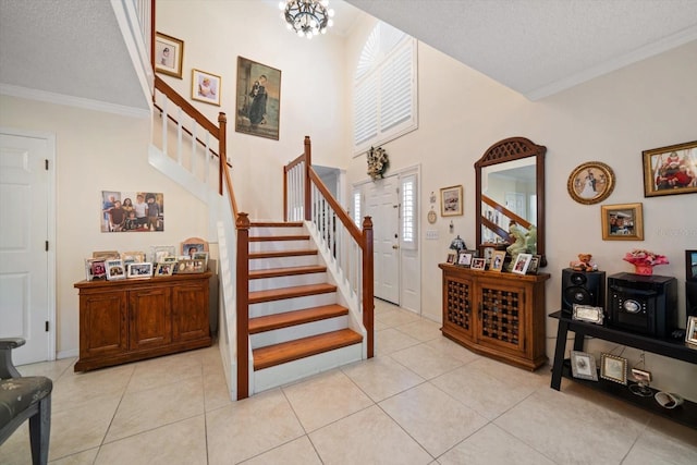 entryway with ornamental molding, light tile patterned flooring, a textured ceiling, and stairs