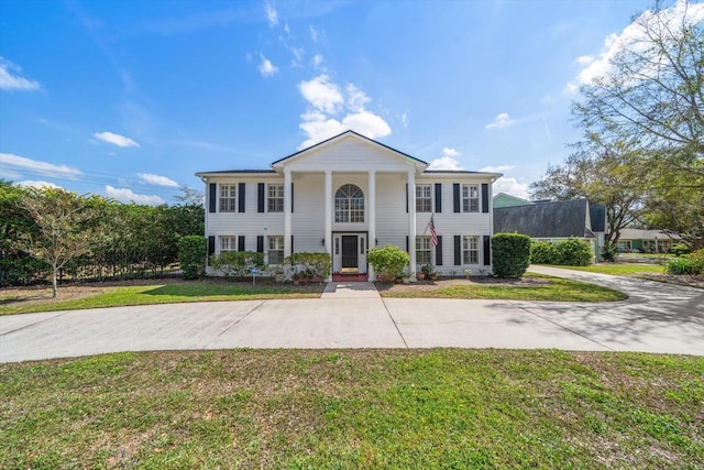 neoclassical home with driveway and a front yard