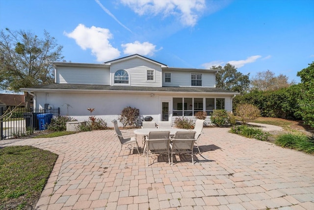 rear view of house featuring a sunroom, stucco siding, fence, and a patio