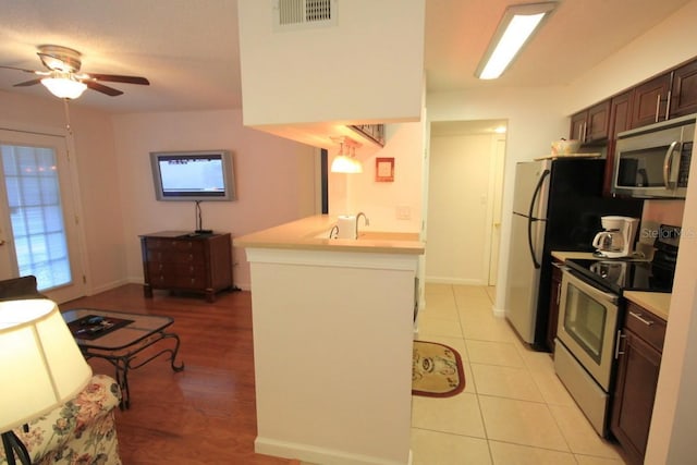 kitchen featuring a healthy amount of sunlight, kitchen peninsula, stainless steel appliances, and dark brown cabinetry