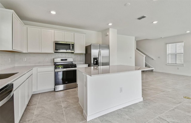 10352 Cross River Trl, Parrish, FL 34219 - kitchen featuring stainless steel appliances, backsplash, a center island, white cabinets, and recessed lighting
