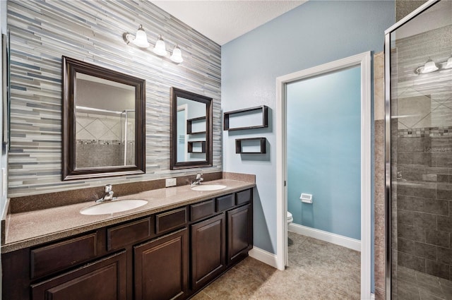 full bath featuring double vanity, a sink, toilet, and a shower stall