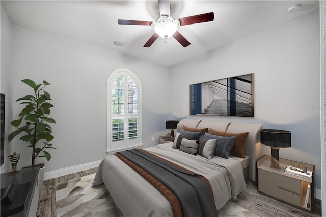 bedroom with a ceiling fan, light wood-type flooring, and baseboards