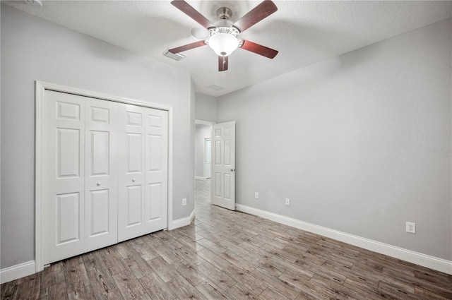 unfurnished bedroom featuring visible vents, baseboards, a ceiling fan, light wood-style floors, and a closet