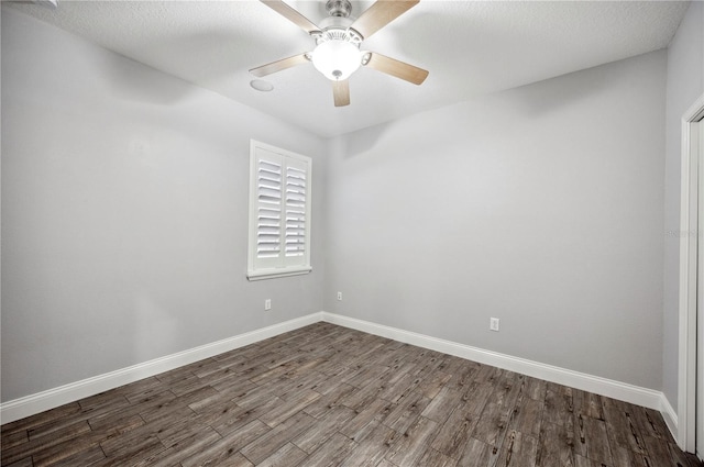 empty room with a textured ceiling, wood finished floors, a ceiling fan, and baseboards