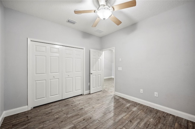 unfurnished bedroom featuring a closet, wood finished floors, visible vents, and baseboards