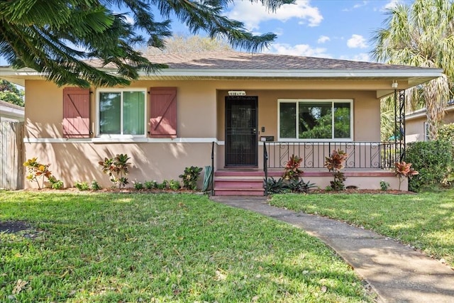 view of front of home with a porch, a front yard, and stucco siding