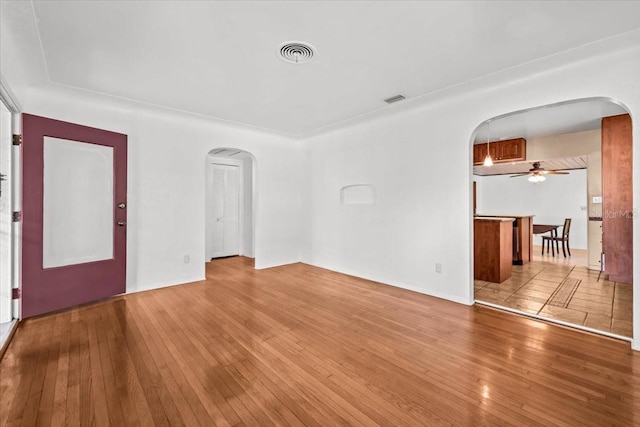 unfurnished room featuring arched walkways, visible vents, and hardwood / wood-style floors