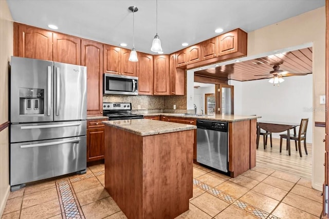 kitchen featuring stainless steel appliances, a peninsula, a kitchen island, hanging light fixtures, and tasteful backsplash