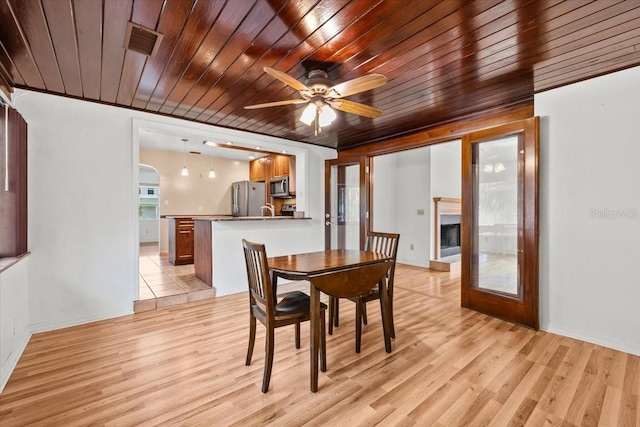 dining area with light wood-style floors, wooden ceiling, visible vents, and a fireplace