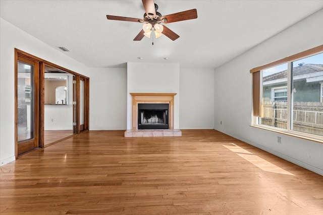 unfurnished living room featuring a fireplace with raised hearth, light wood-style flooring, visible vents, and a ceiling fan