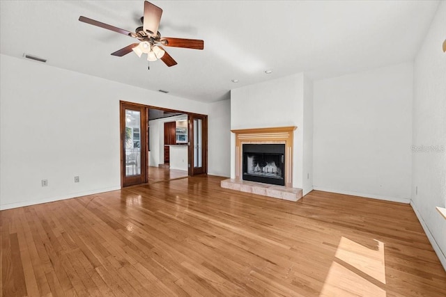 unfurnished living room featuring a fireplace with raised hearth, baseboards, visible vents, and light wood-style floors