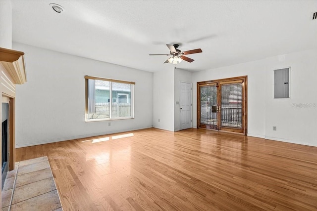 unfurnished living room featuring electric panel, baseboards, visible vents, a ceiling fan, and light wood-style floors