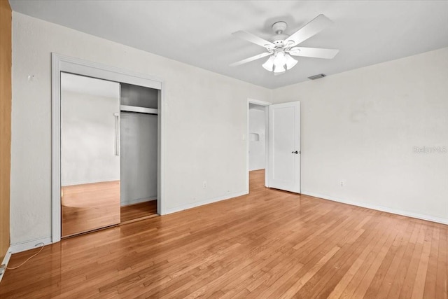 unfurnished bedroom featuring ceiling fan, visible vents, baseboards, a closet, and hardwood / wood-style floors