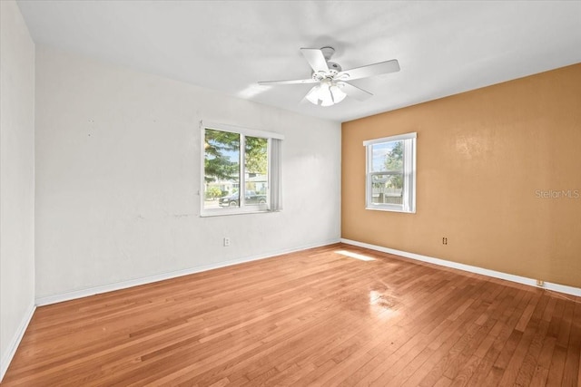 empty room featuring a ceiling fan, baseboards, and light wood finished floors