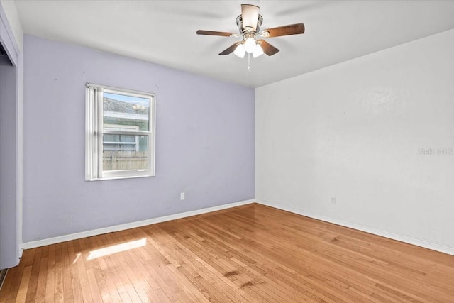 empty room with a ceiling fan, light wood-style flooring, and baseboards