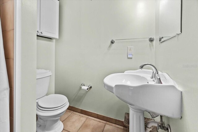 bathroom with tile patterned flooring, baseboards, a sink, and toilet