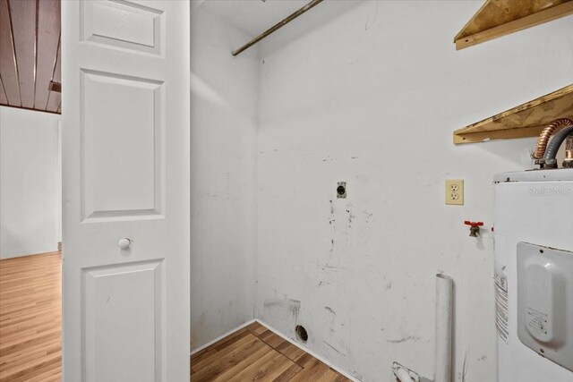 washroom featuring laundry area, wood finished floors, and electric water heater