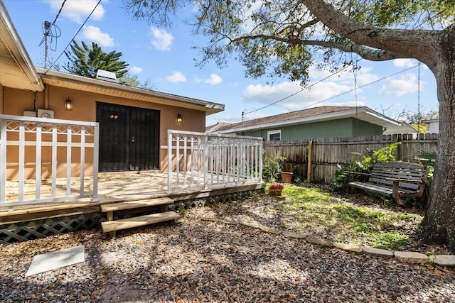 back of property with a fenced backyard, a wooden deck, and stucco siding