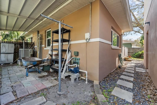 view of side of home with a patio, fence, and stucco siding