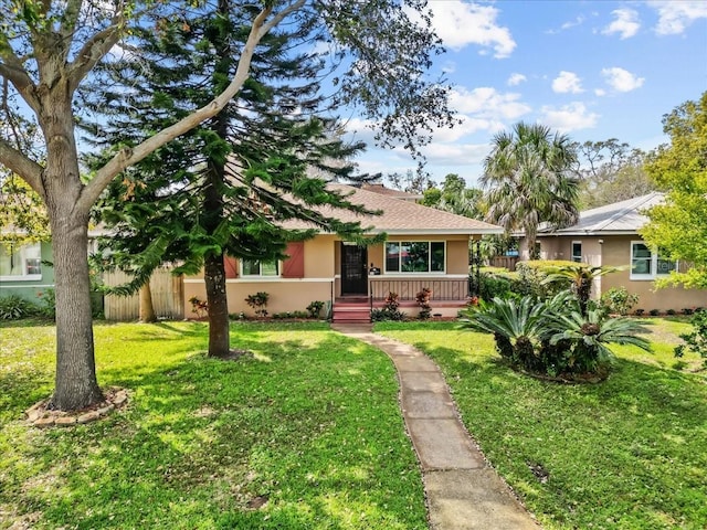 ranch-style home featuring roof with shingles, stucco siding, fence, and a front lawn