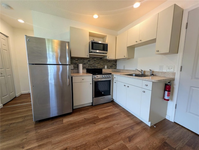 kitchen featuring dark wood-style floors, light countertops, a sink, stainless steel appliances, and backsplash