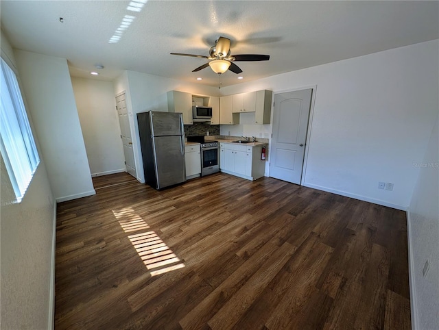 kitchen with dark wood-style flooring, ceiling fan, baseboards, and stainless steel appliances