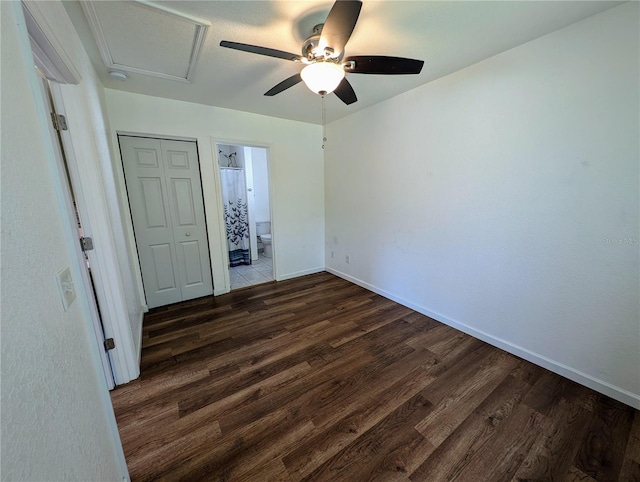 unfurnished bedroom featuring ceiling fan, connected bathroom, a closet, wood finished floors, and baseboards