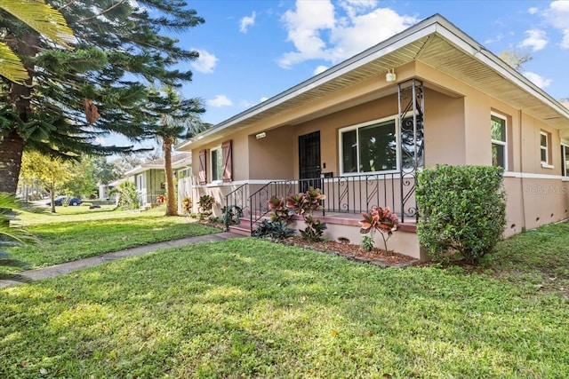 view of front of house featuring covered porch, stucco siding, and a front yard
