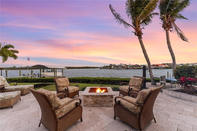 view of patio / terrace with an outdoor living space with a fire pit, a boat dock, and a water view