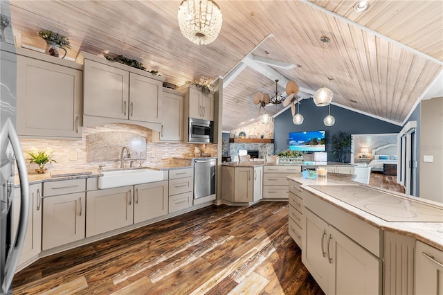 kitchen with dark wood finished floors, a sink, appliances with stainless steel finishes, backsplash, and a chandelier