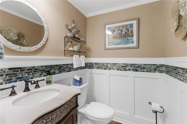 bathroom featuring toilet, a textured ceiling, wainscoting, crown molding, and vanity